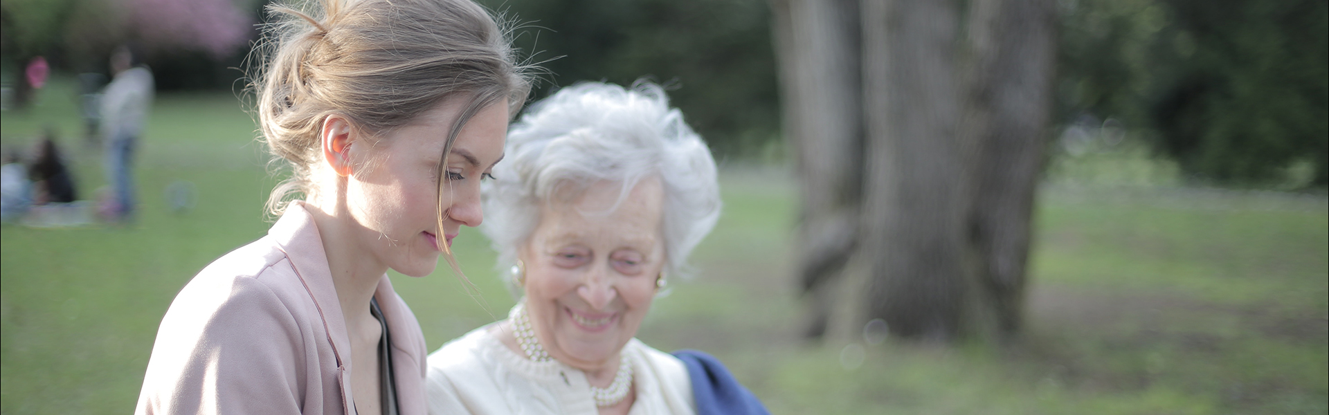 Free Stock photo of a teenage assisting an elderly woman on a bench in a park