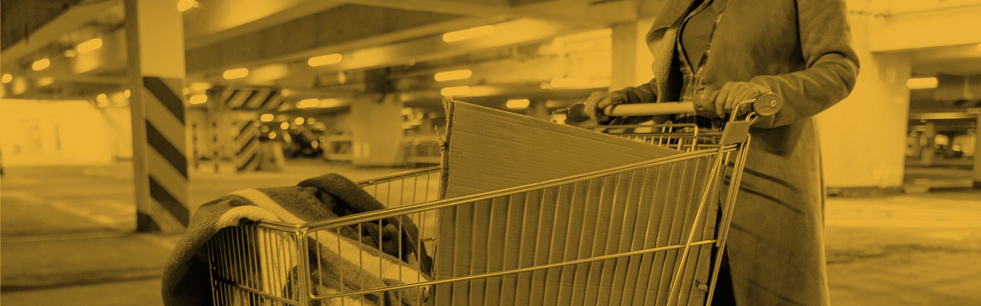 Stock image of a homeless woman pushing a shopping trolley in an empty car park