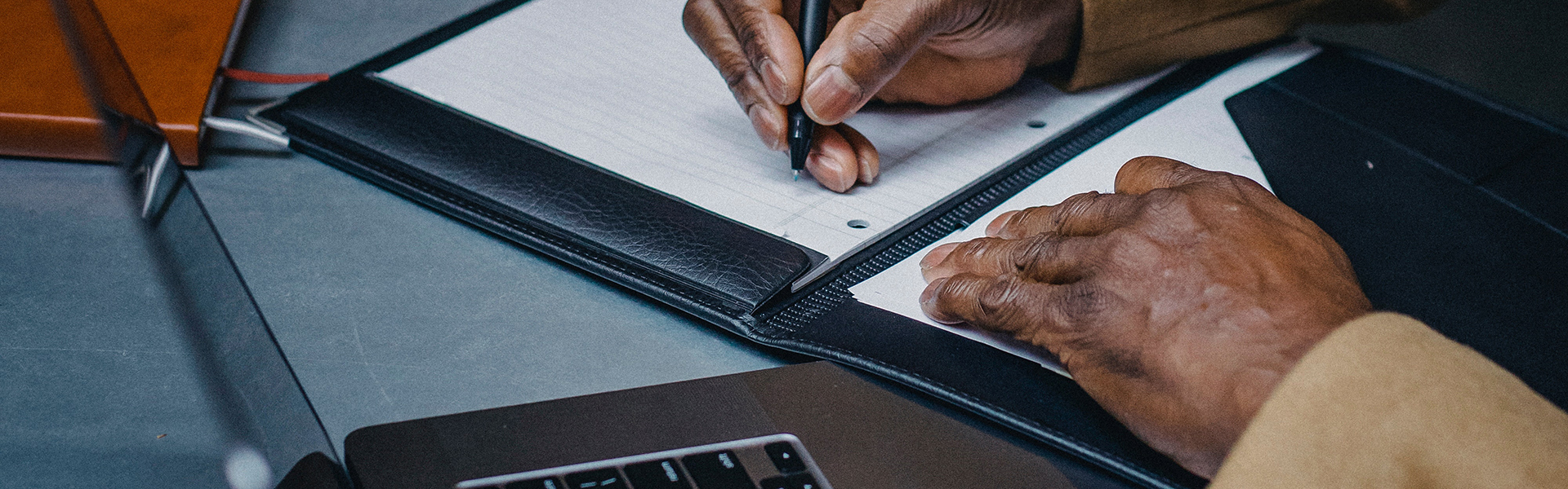 Stock photograph of a mans hands writing in a notebook